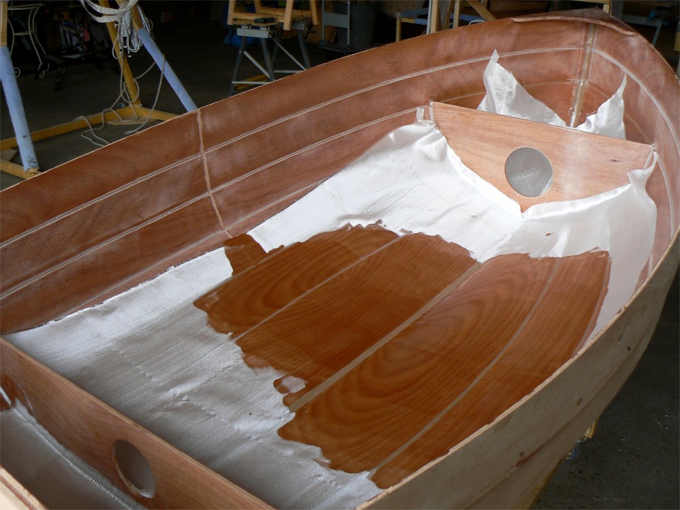 J'ai commencé à saturer le tissu à l'époxy : je viens d'étaler 160 ml de résine et de durcisseur à la raclette. La coque est déjà si rigide que je n'ai même pas eu besoin de mettre de barre d'ouverture pour tenir la forme de la coque en l'absence de la membrure.