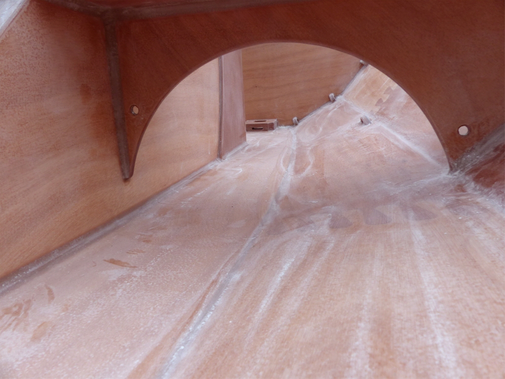 Vue de l'intérieur du Skerry Raid en fin de ponçage, on aperçoit au premier plan la cloison transversale et au fond le pied de mât et les amarrages du coté tribord. 