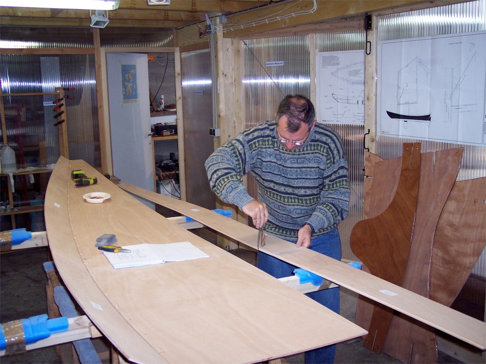 Aussitôt de retour à l'atelier, je reprends avec Gilles la construction accompagnée de son PassageMaker (numéro 34), déjà préparée sur deux matinées. Gilles a cousu le bordé 1 bâbord sur la sole et il trace ici l'écartement pour les futurs trous des sutures qui vont relier le bordé 1 tribord à la sole. 