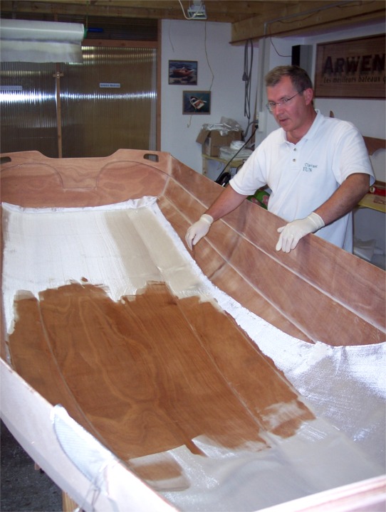 Après le ponçage, nous passons à la stratification du fond de la coque, sur l'intérieur. Voici la photo que j'aime bien vous montrer, avec le tissu de verre partiellement saturé d'époxy. Je ne me lasse pas de m'émerveiller de la façon dont le tissu disparait quand il est mouillé d'époxy... 