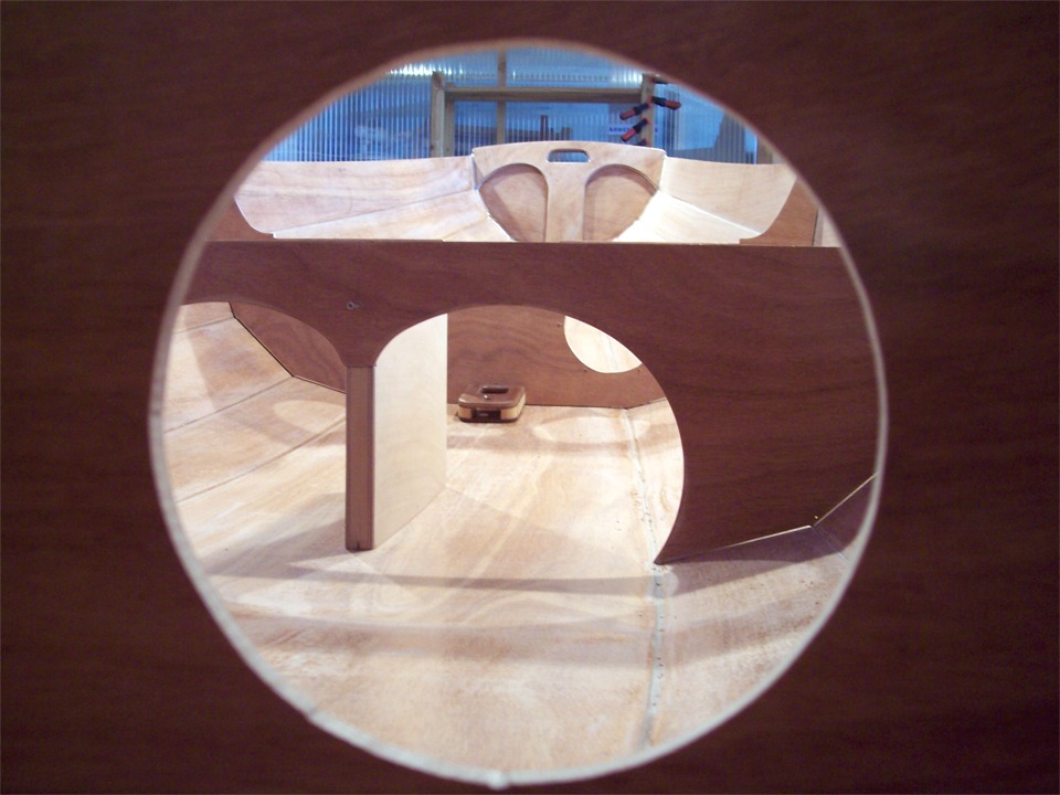 Cette image au cadrage audacieux (et hautement artistique) prise par la découpe de la trappe tribord du compartiment arrière montre le pied de mât au pied de la cloison avant, visible à travers l'allègement de la membrure centrale. Il est juste monté "à sec", sans époxy, de même que l'ensemble de la structure interne et le puits de dérive. On voit d'ailleurs un peu de jour autour de la membrure centrale. Nous allons maintenant démonter le pied de mât et le puits de dérive, les encoller et les remonter, puis nous ferons tous les joints-congés qui tiendront la structure. 