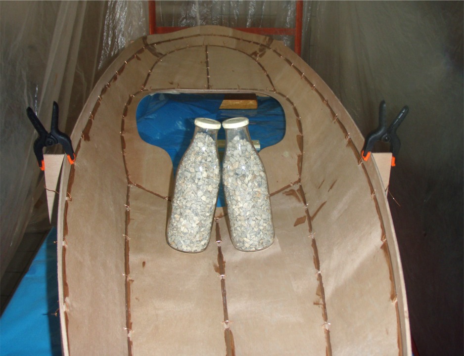 Collage du pontage par la face int&eacute;rieure : il s'agit du premier collage "en pointill&eacute;s" entre les sutures. Charly fera ensuite un second collage en continu apr&egrave;s avoir coup&eacute; et extrait les sutures. Les bouteilles de gravier appuient le pontage sur le gabarit. 