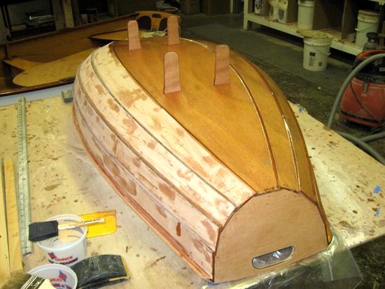 Impr&eacute;gnation du contreplaqu&eacute; &agrave; l'&eacute;poxy "claire", afin de durcir la surface. On voit clairement les "jambes" des membrures qui d&eacute;passent sur l'ext&eacute;rieur. Elles recevront les patins de support r&eacute;versibles. 
