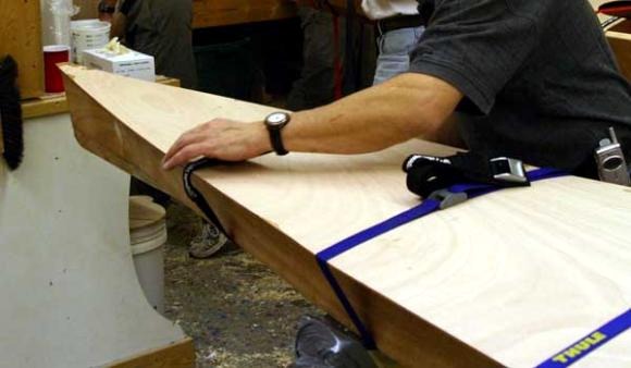 Mise en place du pontage grâce, notamment, à des sangles à boucle autoserrante. Le pontage est "taillé grand" pour tenir compte des légères variations de courbure inhérentes à la construction en cousu-collé. 