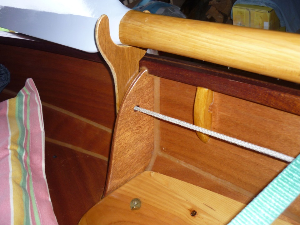 Claude a fix&eacute; une fourche sur la t&ecirc;te de la membrure arri&egrave;re afin de tenir l'aviron lorsqu'il n'est pas utilis&eacute;. N'ayant pas vu l'autre face de la fourche, je suppose qu'elle est plaqu&eacute;e contre la membrure par un noeud en huit dans la garcette que l'on voit sortir &agrave; travers la membrure et qui doit aller sur un taquet vers l'avant. Un &eacute;paulement assoit la fourche sur la serre, et je suppose qu'elle se prolonge vers le bas pour reposer sur le dessus du caisson arri&egrave;re. Notez aussi le joli petit filoir un peu en avant de la membrure : un &eacute;l&eacute;gant &eacute;l&eacute;ment de solution au probl&egrave;me de l'abondance de bouts &agrave; saisir dans un petit bateau. La planche en sapin visible dans le bas de l'image est le coin arri&egrave;re d'un banc lat&eacute;ral amovible, qui am&eacute;liore nettement le confort pour la pratique de la voile en Skerry. 
