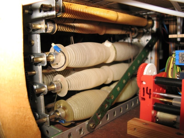 Voici l'une des "boites de brassage" pour un phare. On voit clairement 3 des 5 ou 6 treuils (5 pour misaine et artimon et 6 pour le grand-mât). Les engrenages qui les actionnent sont à l'autre extrémité. Ces treuils sont à double action : ils bordent un bras d'un coté et choquent de l'autre coté. Leur forme renflée alliée à une gorge filetée permet de varier la longueur de manoeuvre bordée ou choquée afin que le changement d'angle reste constant. Les rouleaux en haut des cages ont aussi une gorge filetée et servent à guider les bras sur les bobines en dessous. 