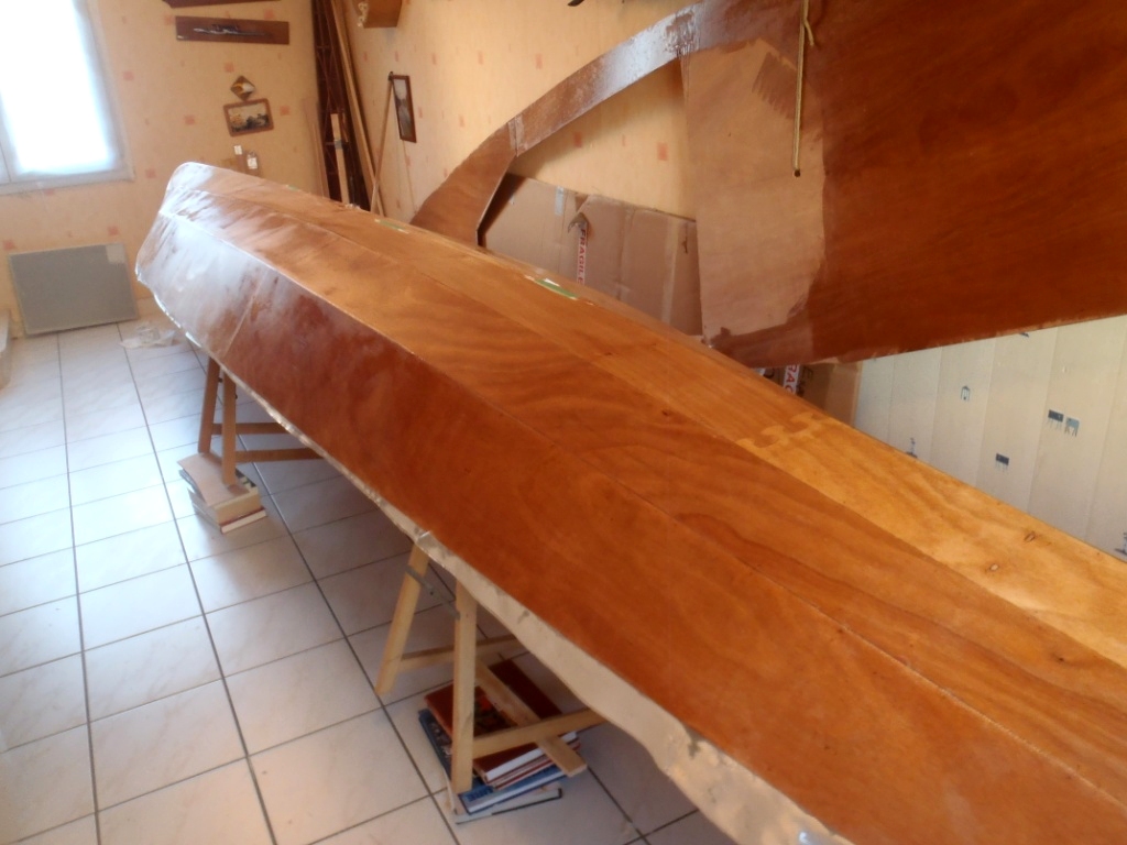 Et voil&agrave; ce que cela donne apr&egrave;s saturation du tissu de verre &agrave; l'&eacute;poxy. Didier nous dit que cette stratification ajoute 1.7 kg au poids de la coque. Notez que le pont a aussi &eacute;t&eacute; pass&eacute; &agrave; l'&eacute;poxy et que Didier n'a pas termin&eacute; la d&eacute;coupe du la partie arri&egrave;re de l'ouverture du cockpit, on voit la zone en demie lune &agrave; d&eacute;couper qui n'a pas &eacute;t&eacute; trait&eacute;e &agrave; l'&eacute;poxy. 