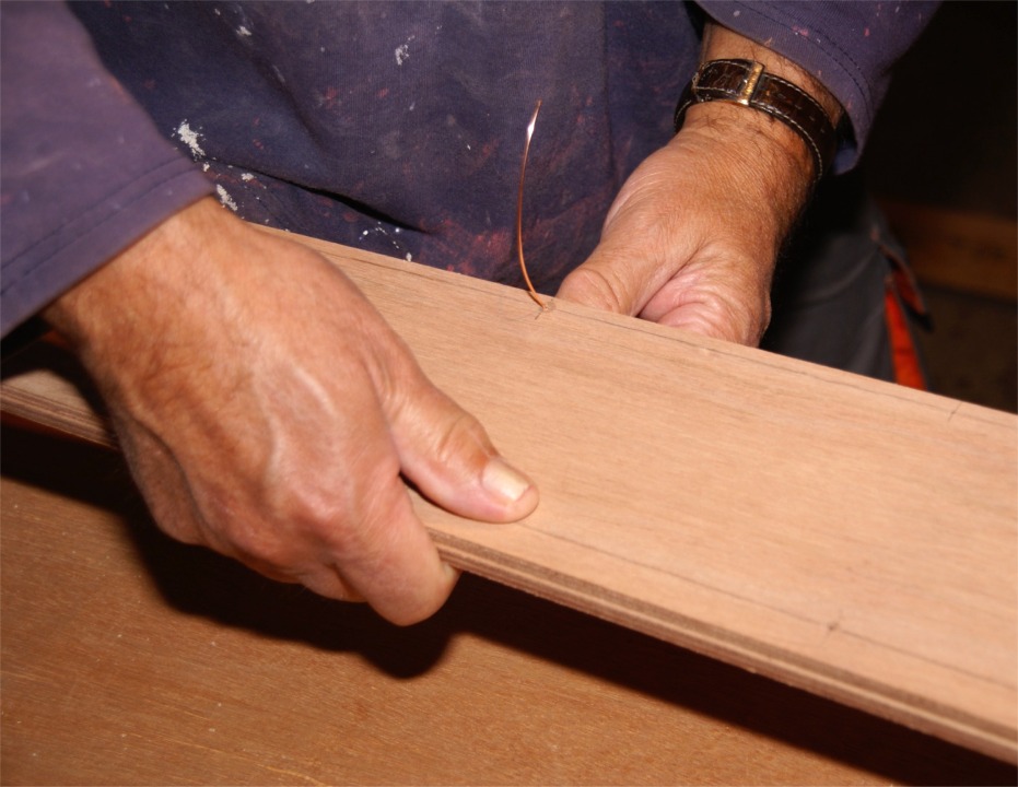 Jean passe une suture à travers les bordés 1, sur le bord qui constituera la ligne de quille. Sur ce joint, on voit que les trous ne sont qu'à 6 mm du bord, car il n'y a pas de feuillure à enjamber. 