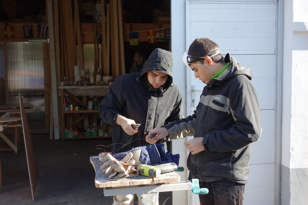 Cyrille et Denis coupent des longueurs de 10 cm de fil de cuivre que nous utiliserons pour suturer les panneaux de coque. 