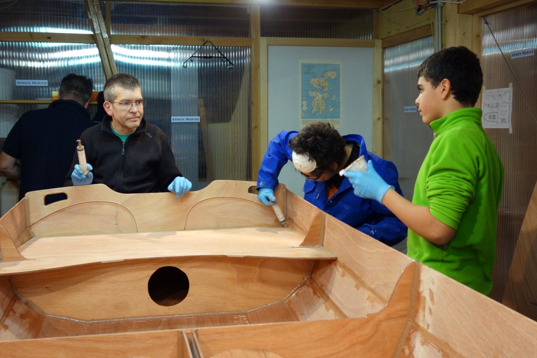Marie-Pierre et Jean d&eacute;posent un gros cordon d'&eacute;poxy charg&eacute;e sur le pourtour de ces pi&egrave;ces, au contact de l'int&eacute;rieur du bord&eacute;. Ce joint sera ensuite liss&eacute; &agrave; la cuiller (et au "b&acirc;ton d'eskimo" l&agrave; o&ugrave; ce joint est tr&egrave;s large, comme dans les angles avant. Nous utilisons d&eacute;cid&eacute;ment des outils tr&egrave;s sophistiqu&eacute;s !) 