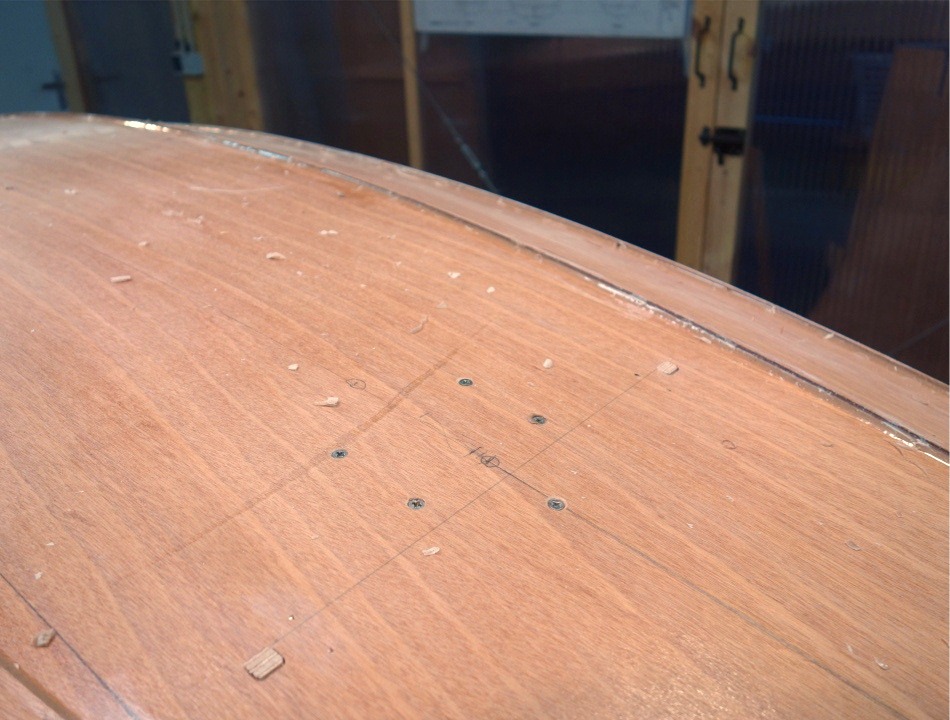 Vue des 4 vis inox qui tiennent l'emplanture du m&acirc;t sur la sole, et la 5e dans l'axe est l'une des deux vis qui tiennent le bas du renfort interne du caison avant. 