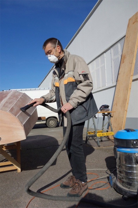 Jean passe un coup d'aspirateur pour &eacute;liminer la poussi&egrave;re apr&egrave;s le pon&ccedil;age g&eacute;n&eacute;ral de la surface ext&eacute;rieure, en pr&eacute;lude &agrave; la stratification.