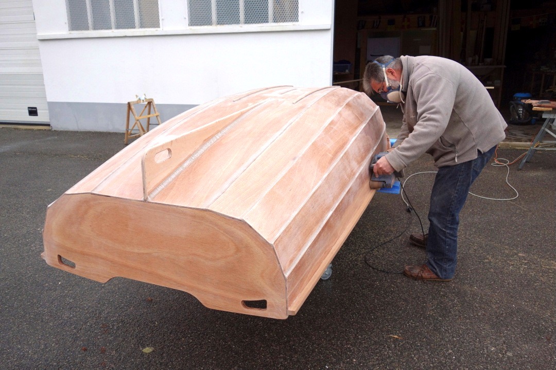 Nous retournons ensuite la coque pour &eacute;liminer &agrave; la ponceuse &agrave; bande les exc&egrave;s d'&eacute;poxy sous les listons. Il faut &ecirc;tre attentif &agrave; ce que la tranche sup&eacute;rieure de la bande abrasive n'attaque pas le bord&eacute;. 