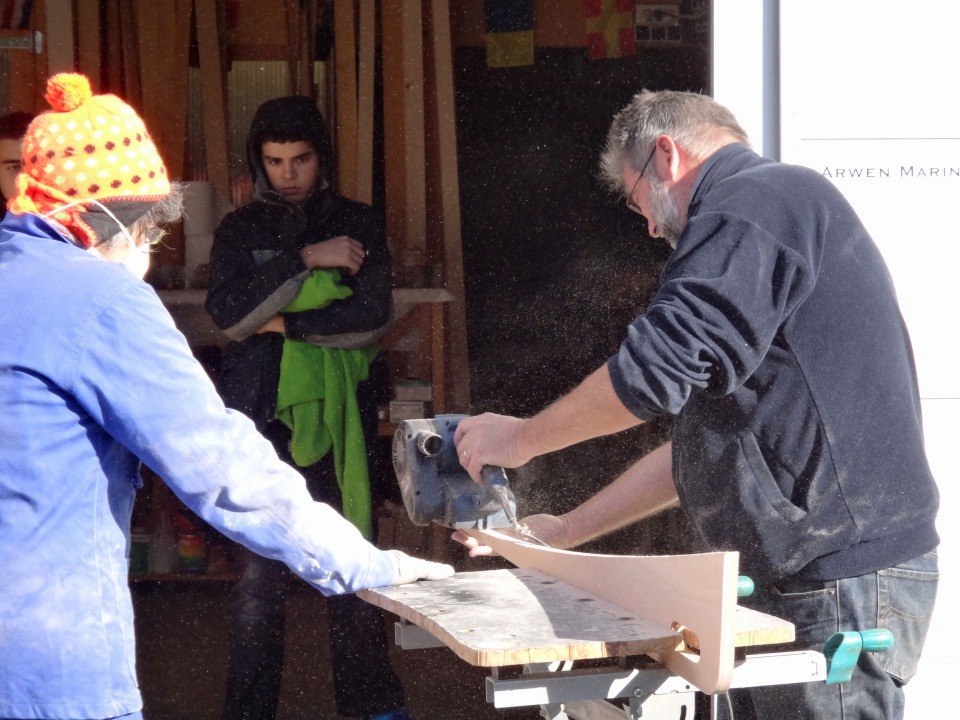 D&eacute;monstration de la ponceuse &agrave; bande : j'&eacute;limine les bavures de collage des deux &eacute;paisseurs de l'aileron. C'est mal : je ne porte pas mon masque anti-poussi&egrave;re, contrairement &agrave; Marie-Pierre. 