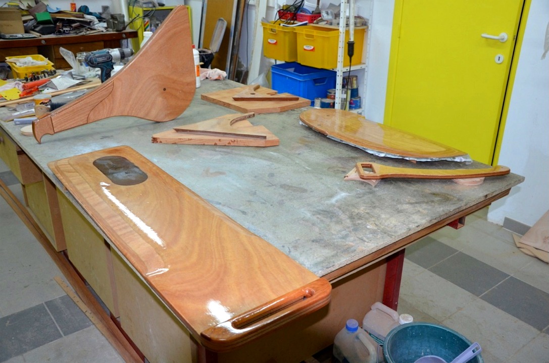 La d&eacute;rive, au premier plan, puis le gouvernail &agrave; gauche, le timon &agrave; droite et le safran. Au centre, il semble que les guirlandes en contreplaqu&eacute; vont bient&ocirc;t laisser place &agrave; des pi&egrave;ces en bois massif. Notez l'insert en plomb dans la d&eacute;rive, qui &eacute;vite que celle-ci flotte dans son puits et remonte toute seule, et donne un petit coup de pouce &agrave; la stabilit&eacute;. Francis l'a envelopp&eacute;e d'une stratification comme c'est encore visible sur le safran, sur lequel le tissu de verre qui d&eacute;passe sur les bords n'a pas encore &eacute;t&eacute; coup&eacute;. 