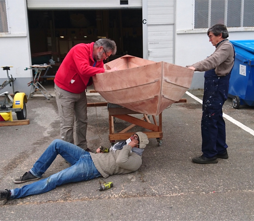 Nous remettons la coque à l'endroit pour fixer les trois paires de cale-pieds. Damien est en position pour visser les deux vis qui tiennent chacun des cale-pieds en plus du collage à l'époxy. 