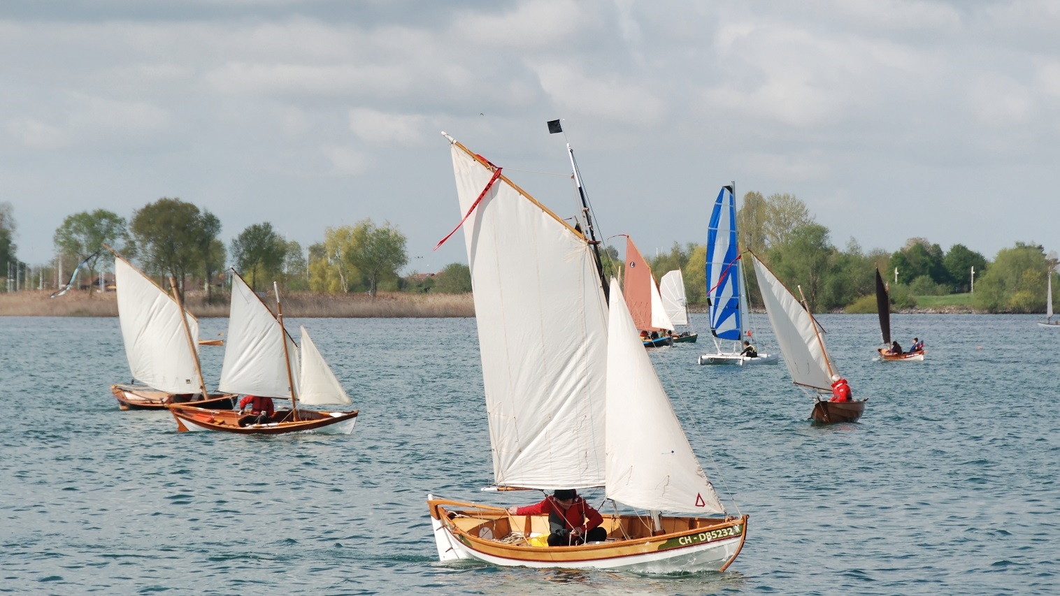 Un catamaran moderne s'est fourvoy&eacute; au milieu de la r&eacute;gate improvis&eacute;e. De gauche &agrave; droite : le Doris 17 "Aldies II", le Doryplume "Love Dory", le Skerry "Anouket", l'Ilur "Tournepierre", le Skerry "Piff", le Doryplume "Prise de Ris'k" et le Skerry "Pirate du Rh&ocirc;ne". 