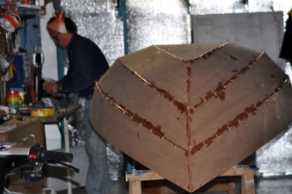Denis est ici &agrave; l'arri&egrave;re-plan &agrave; moiti&eacute; cach&eacute; par la lampe, pendant que le premier collage de son Skerry commence &agrave; durcir. Pour la prochaine &eacute;tape, Denis va couper et extraire les sutures en fil de cuivre. 