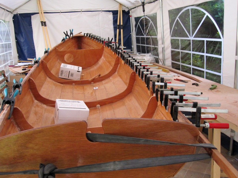 Collage du liston tribord, cette fois-ci sur l'ext&eacute;rieur du bord&eacute;, comme il se doit pour un liston. De la sorte, Herv&eacute; "sandwiche" le haut du bord&eacute; en contreplaqu&eacute; entre deux bois massifs. M&eacute;caniquement, le r&eacute;sultat est aussi rigide, l'avantage est de prot&eacute;ger la tranche du contreplaqu&eacute;, et puis il y a l'esth&eacute;tique, au go&ucirc;t de chacun. Notez l'utilisation de la chambre &agrave; air &agrave; l'arri&egrave;re, o&ugrave; la pr&eacute;sence des courbes interdit de poser des presses. Sur b&acirc;bord, la serre est mont&eacute;e &agrave; sec, en attendant la lib&eacute;ration des presses de tribord. 