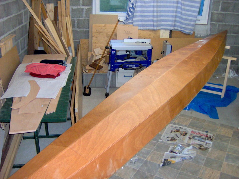 Sur cette image, Dominique vient de stratifier l'ext&eacute;rieur de la coque : un tissu de verre est rendu solidaire du contreplaqu&eacute; par un collage &agrave; la r&eacute;sine &eacute;poxy. Le r&eacute;sultat est un composite bois-verre-&eacute;poxy qui donne une bonne rigidit&eacute; &agrave; la longue coque (6.25 m) de l'Oxford Shell. 