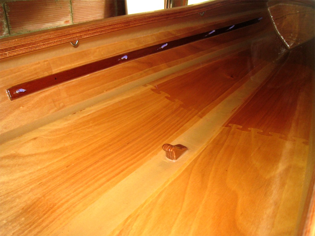 Voici justement l'int&eacute;rieur du cockpit. La barre lat&eacute;rale comporte 6 vis qui vont servir &agrave; fixer les rails de trois cale-pieds par cot&eacute; : une paire pour la position avant, une seconde pour la position arri&egrave;re et une troisi&egrave;me au centre pour la position centrale ajout&eacute;e par Franck pour l'utilisation en solo. Le taquet fix&eacute; sur le joint central sert &agrave; tenir l'arri&egrave;re du dosseret de la position avant, comme on le voit sur la photo suivante. 