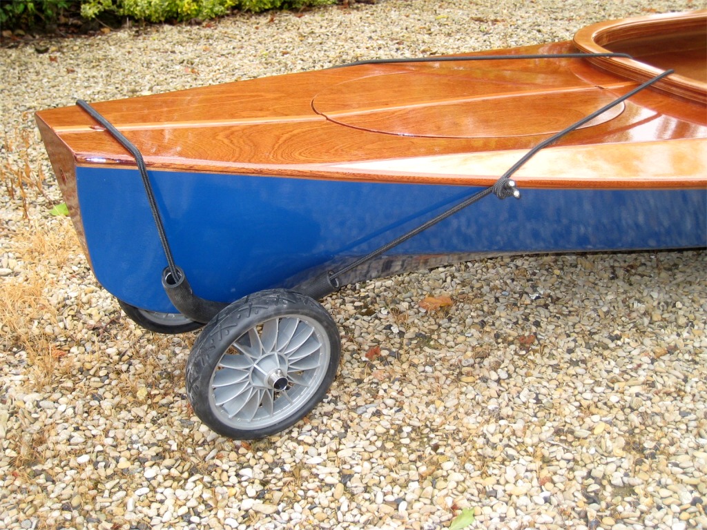 Le petit chariot de transport se fixe à une extrémité du kayak (ici l'arrière), et on porte l'autre extrémité. C'est moins lourd mais surtout beaucoup moins encombrant que de porter seul les 27.2 kg du Wood Duck Double (on met le rebord de l'hiloire sur l'épaule, et attention aux trournants et à la prise au vent !) 