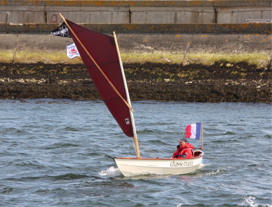Didier a repris sa route sur la nouvelle amure et le pli a totalement disparu lorsqu'il a bordé sa voile. Cette image montre un autre aspect intéressant de la voile à livarde : lorsque le vent est fort, il cintre le mât et fait déverser la partie haute de la voile, ce qui réduit le couple de chavirement et contribue à rendre ce gréement plus sûr pour un petit bateau. 