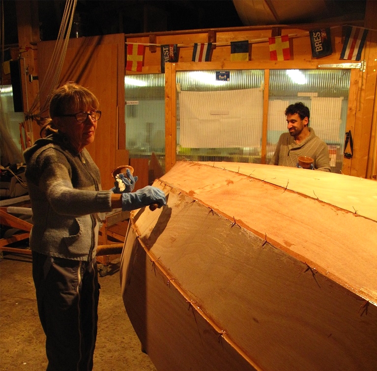 Collage : nous avons remis la coque &agrave; l'endroit le temps de faire les gros joints-cong&eacute;s de l'&eacute;trave et de l'&eacute;tambot, ainsi que ceux de la face avant de la cloison avant et de la face arri&egrave;re de la cloison arri&egrave;re, puis nous avons remis la coque &agrave; l'envers afin de faire le collage des panneaux des panneaux de coque. Nous avons d&eacute;pos&eacute; dans chaque joint entre les panneaux de coque un filet d'&eacute;poxy l&eacute;g&egrave;rement charg&eacute;e : la colle doit &ecirc;tre assez fluide pour bien p&eacute;n&eacute;trer jusqu'au fond des joints, mais pas trop afin de ne pas couler &agrave; travers. Nous lissons ensuite lle joint de colle afin de le pousser au fond des joints, puis nous raclons les exc&eacute;dents afin de limiter le travail de pon&ccedil;age &agrave; venir. 