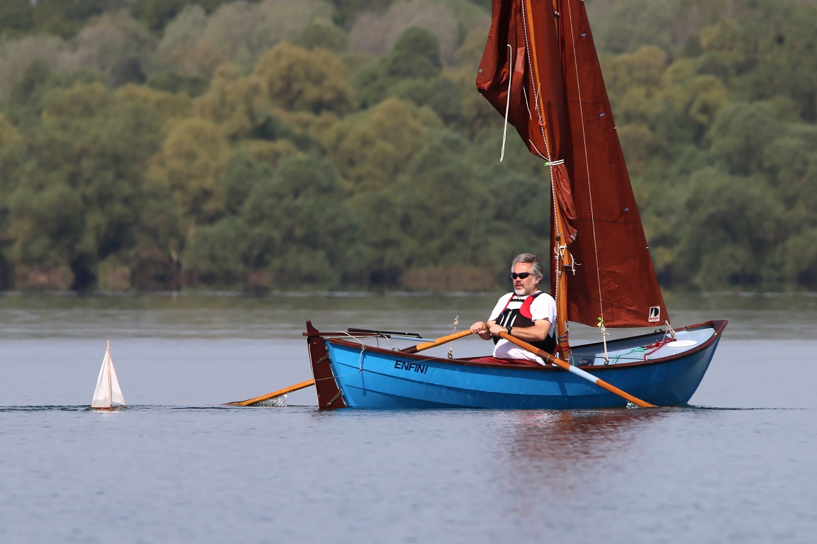 Le Whilly Boat "ENFIN!" remorque un petit voilier jouet. 