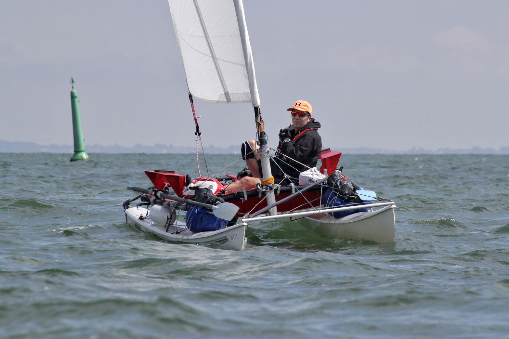 Jean-David à bord de son Hobie Cat 16 modifié : largeur réduite pour pouvoir ramer, remplacement du gréement trop lourd et trop puissant pour une personne seule par un voile de 9 m2 sur mât enrouleur, et remplacement du trampoline textile par une plateforme rigide.