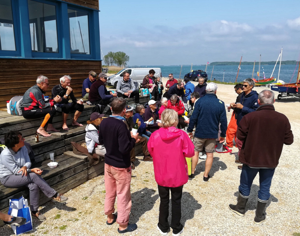 Rassemblement de ceux qui sont déjà arrivés pour le premier pique-nique sous le soleil, comme promis par la météo, contrairement à ce qu'elle nous annonce pour le lendemain samedi : vent de 15 à 30 noeuds avec pluie et 4°C le matin. Photo : Laurent C. 