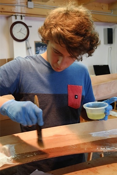 Ga&euml;l utilise un pinceau pour saturer la fibre de verre et chasser les bulles. Les bandes deviennent ainsi transparentes et se plaquent sur le bois et le joint. 