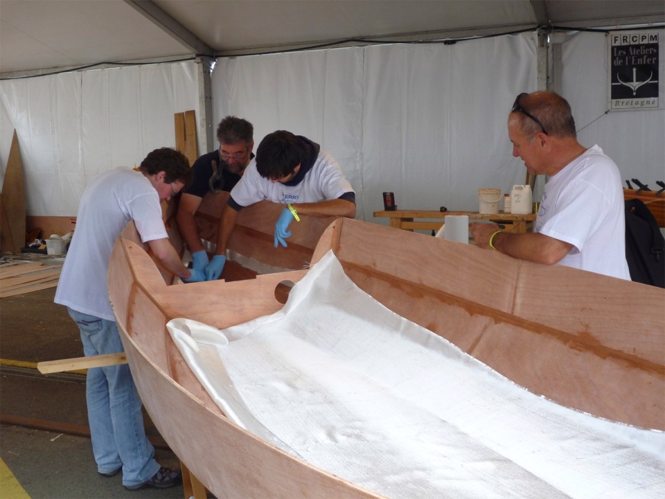Nous avons disposé les pièces de tissu de verre dans la coque et commençons par saturer la fibre de verre à l'intérieur du compartiment étanche, afin de se faire la main sur une zone qui sera invisible une fois le bateau terminé. 
