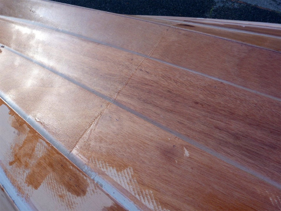 Cette vue des trois bord&eacute;s de fond b&acirc;bord montre la lisi&egrave;re du renfort de la poupe. Les traces d'&eacute;poxy montrent que j'avais commenc&eacute; &agrave; saturer une autre pi&egrave;ce de tissu de verre plus grande et de grammage plus lourd, que j'ai finalement ot&eacute;e car je n'arrivais pas &agrave; &eacute;liminer les bulles sur les clins, pour la remplacer par la pi&egrave;ce visible ici, plus petite et plus fine (162 g/m2), largement suffisante. 