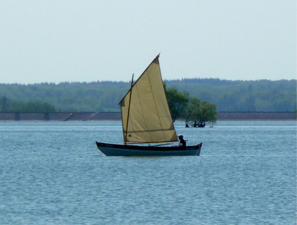 Ludo a choisi de gréer son Skerry d'une misaine au tiers, au lieu de la voile à livarde prévue. Il a acheté sa voile d'occasion, magnifique en Dacron écru, et l'a retaillée pour réduire un peu sa taille. Je ne connais pas sa surface exacte, mais on est encore clairement bien au-dessus des 5.10 m2 de la voile à livarde standard. 