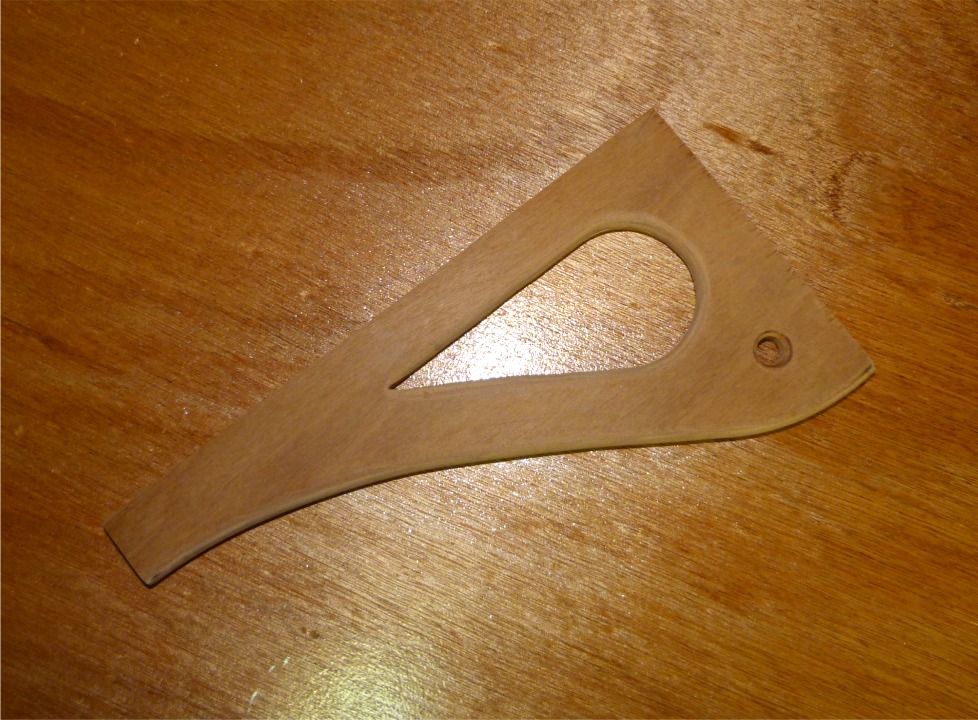 Entretemps j'ai découpé une autre pièce en CP makoré de 12 mm qui sera collée sur la face arrière du puits de dérive, sous le banc central. Le trou rond dans l'angle supérieur extérieur sera le capelage de l'écoute de grand-voile. L'ouverture en goutte d'eau a pour but d'alléger (surtout visuellement) la pièce. 