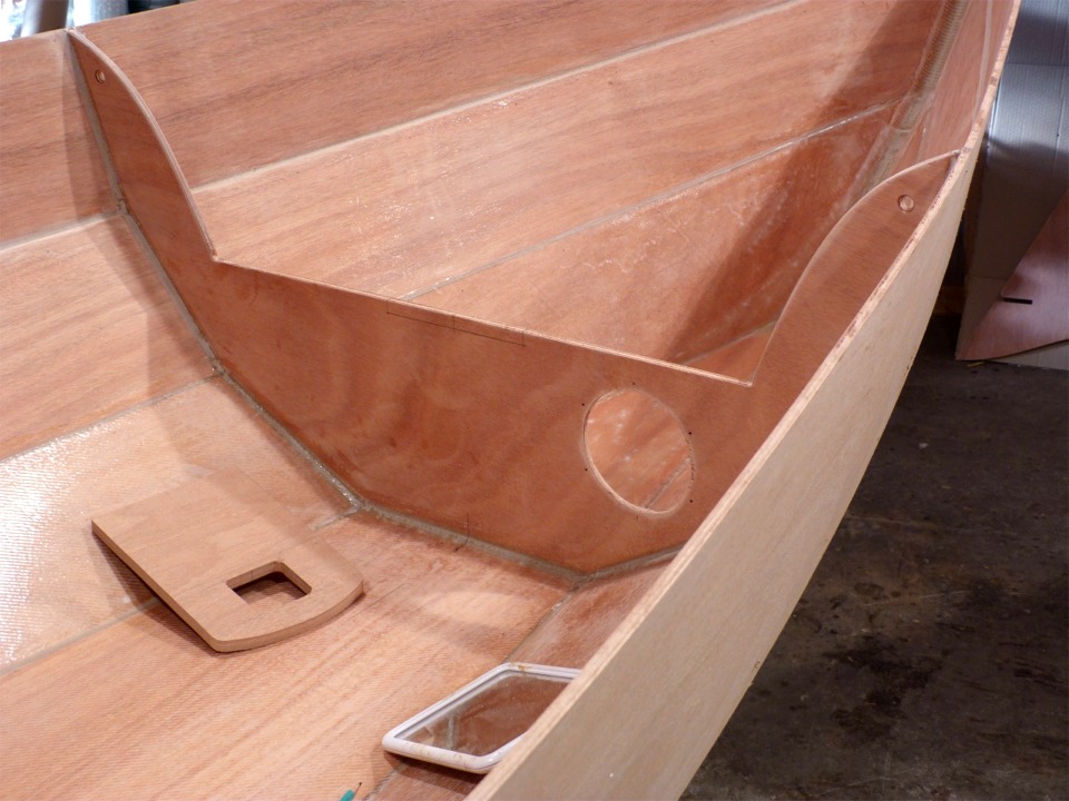 Je terminais ma mise à jour précédente en annonçant la pose prochaine du pied de mât et des dessus de caisson sur "Gustave". C'est à cet effet que j'ai sorti le petit miroir que l'on aperçoit au pied de la cloison du compartiment étanche avant (il me sert à vérifier que le dessus de caisson est bien jointif avec le haut de la cloison). J'ai aussi découpé un renfort d'étambrai plus sérieux que celui fourni avec le kit, qui me parait un peu léger. Celui-ci est coupé dans du contreplaqué makoré de 12 mm, et surtout il se prolonge au-delà de la cloison, qui doit donc être entaillée. 