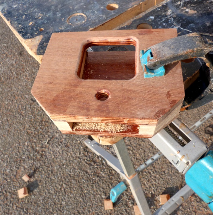 Je donne trois coups d'égoïne pour éliminer les bouts des cales en sapin. J'avais percé les trous et arrondi les arêtes intérieures à la défonceuse avant le collage. Le pied est ouvert sur sa face arrière afin que l'eau ne reste pas à croupir au fond. Le petit trou peut servir à saisir une poulie de renvoir, par exemple. 