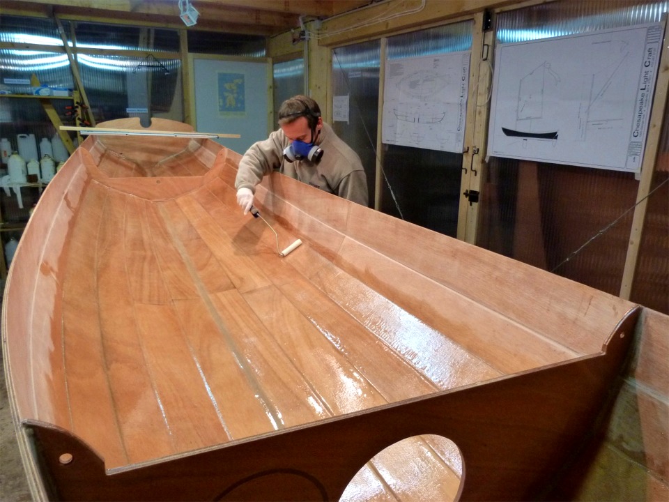 Quatre heures apr&egrave;s avoir fini de saturer le tissu de verre, Arnaud passe une nouvelle couche d'&eacute;poxy au rouleau sur toute la surface stratifi&eacute;e afin de "remplir la trame" du tissu. En effet, lors de la stratification, on ne met pas trop d'&eacute;poxy car le tissu doit &ecirc;tre satur&eacute; mais sa trame doit &ecirc;tre clairement apparente. Si on mettait trop de r&eacute;sine, le tissu risquerait de "flotter" et le composite CP-fibre de verre-&eacute;poxy ne serait pas homog&egrave;ne. On laisse donc durcir partiellement la stratification "maigre", puis on ajoute une nouvelle couche de r&eacute;sine par dessus, et cette nouvelle couche va fusionner avec la premi&egrave;re, d&eacute;j&agrave; assez durcie pour que le tissu reste bien coll&eacute; au CP. Le but de cette seconde couche est esth&eacute;tique : il s'agit de r&eacute;duire le relief caus&eacute; par la trame afin que le tissu devienne totalement invisible sous le vernis ou la peinture. 