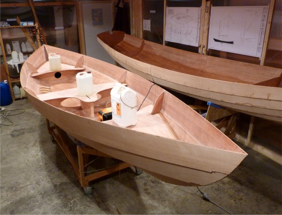 Et vue de l'avant. Les bidons servent &agrave; presser les collages. On voit que je garde la Yole de Chester &agrave; l'int&eacute;rieur de la partie chauff&eacute;e de l'atelier (m&ecirc;me si ce n'est que par intermittence) car le reste de l'atelier est &agrave; 2&deg;C, un peu bas pour que l'&eacute;poxy de sa stratification poursuive son durcissement... Notez que j'ai fait la pr&eacute;-ouverture du puits de d&eacute;rive dans le banc central : la fente que j'ai faite &agrave; la scir sauteuse ne fait que 16 mm de large, je me suis conserv&eacute; une marge de manoeuvre de 2 mm de chaque cot&eacute;, que j'&eacute;liminerai &agrave; la d&eacute;fonceuse. 