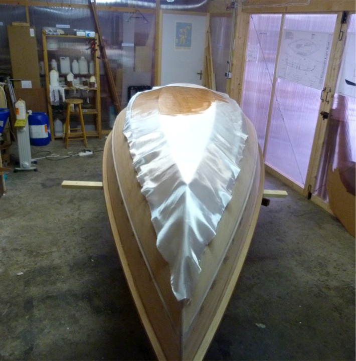 Une fois l'&eacute;poxy des retouches durcie, je reponce et je passe &agrave; la stratification : je cr&eacute;e un composite en liant une couche de fibre de verre au contreplaqu&eacute; gr&acirc;ce &agrave; la r&eacute;sine &eacute;poxy. Comme pour l'int&eacute;rieur, cette stratification ne couvre que la sole et les deux premiers bord&eacute;s. 