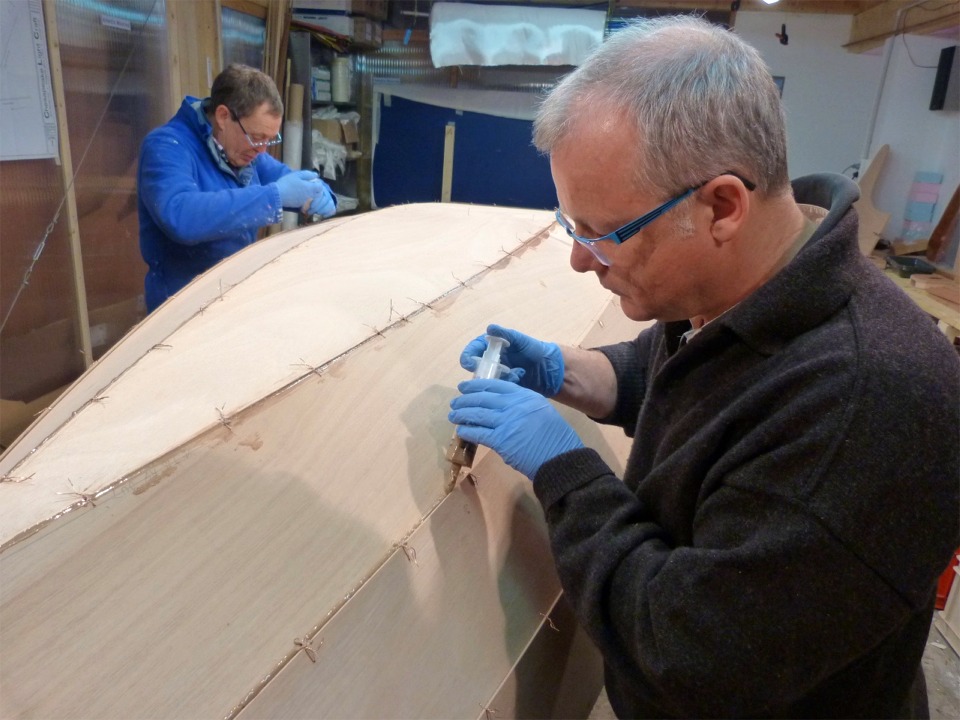 Nous avons sorti "Gustave" de la partie chauffable de l'atelier et le nouveau Skerry l'y remplace afin de passer au premier collage : nous avons retourn&eacute; la coque, puis Jacques et Herv&eacute; d&eacute;posent &agrave; la seringue un filet d'&eacute;poxy charg&eacute;e dans tous les joints. 