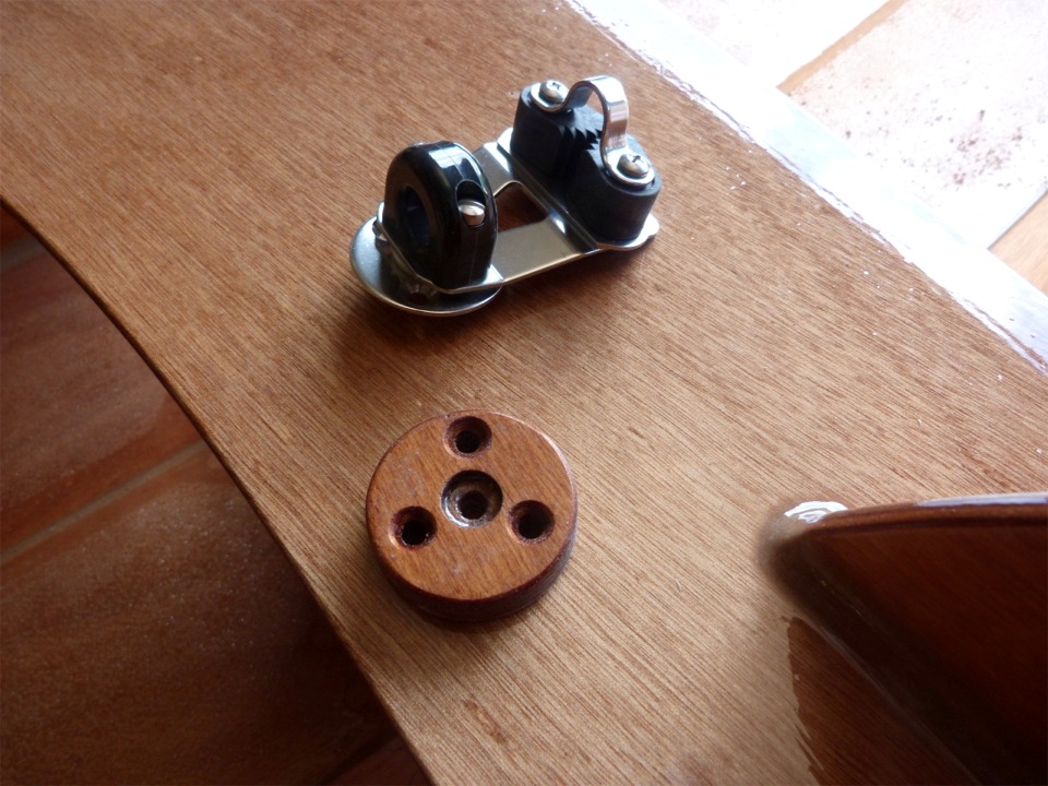 Je suis aussi tr&egrave;s content des deux pastilles de CP de 12 mm que j'ai pr&eacute;par&eacute;es pour fixer les filoirs de foc sur les bords du banc milieu. L'embase ronde en plat d'inox est emboutie pour les trois vis frais&eacute;es de fixation, et j'ai donc frais&eacute; les trois trous dans la pastille, et le trou central correspond au relief du pivot serti : la platine qui porte le coinceur pivote &agrave; 360 &deg; avec le filoir. Les filoirs sont boulonn&eacute;s &agrave; travers la pastille et le banc. 