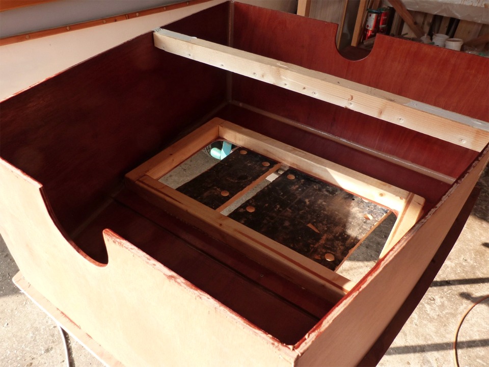Voici l'intérieur du coffre, après assemblage (par joints-congés) du dessus et des cotés verticaux. Un cadre en pin sous le cadre de CP autour de l'ouverture de la trappe raidit le bord de cette ouverture. Les faux trous de godille seront les ouvertures du tunnel qui chevauchera la tête de dérive : le bout de relevage de la dérive doit passer sous le coffre pour revenir près de la main du barreur. 