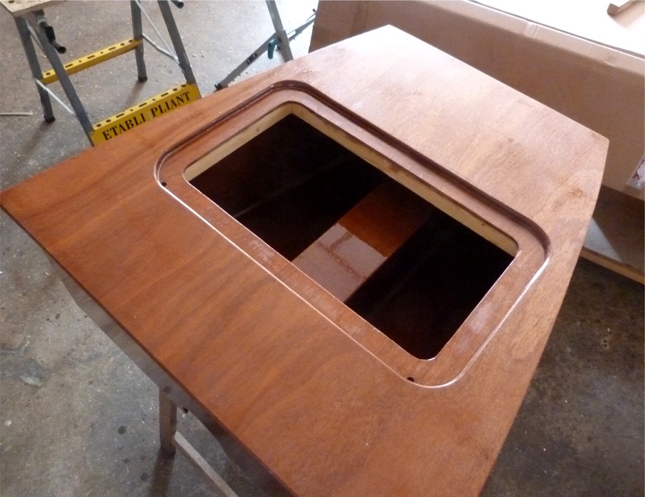 Cette image montre clairement le cadre de trappe rapporté sous le panneau de CP de 12 mm, qui permet de mettre le dessus de la trappe d'accès de niveau. Le "tunnel" interne divise le coffre en deux compartiments de rangement. Pierre a percé deux trous dans les angles arrière de la découpe du panneau afin de connecter des durites (tous carburants) débouchant dans les angles arrière du coffre et permettant d'évacuer l'eau de pluie ou de mer qui resterait sinon piégée autour de la trappe. 