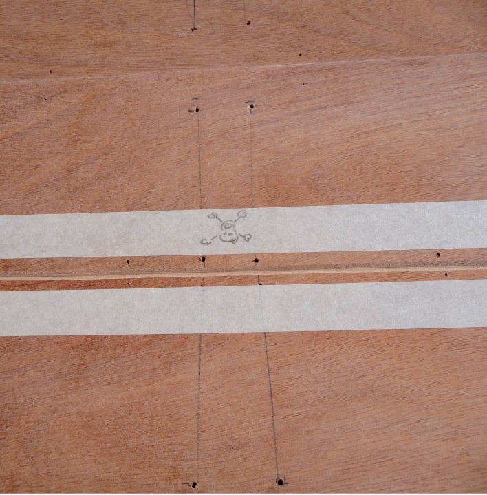 Gros plan sur les bandes Gordini au niveau de la membrure avant. Celle-ci est déposée et on aperçoit son tracé d'empreinte et les trous de ses sutures. La tête de mort artistiquement dessinée par Emmanuel rappelle l'interdiction de boucher les trous des sutures, qui seront à réutiliser. 
