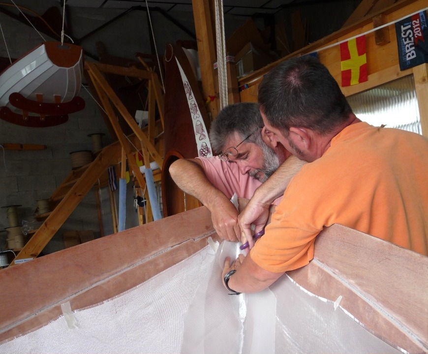 La verticalité des parois dans le compartiment avant nécessite de coller le haut du tissu de verre. Trois pièces se recouvrent dans l'étrave afin de renforcer cette partie du bateau et éviter la multiplication des plis. 