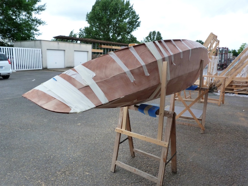 Nous voila pr&ecirc;ts &agrave; coller le pont sur la coque. La bande adh&eacute;sive tient fermement le pont sur la coque en fermant le joint au livet. Nous avons viss&eacute; des bouts de tasseau sur les tr&eacute;teaux pour pouvoir caler le Wood Duck sur la tranche afin de faire le joint coque-pont qui se trouve vers le bas (ici tribord), puis nous tournerons le kayak sur l'autre cot&eacute; pour faire le joint b&acirc;bord. 