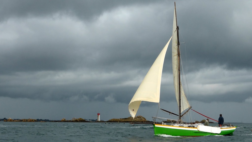 Jolie image de Reder Noz par Alban, avec le phare de La Croix à l'arrière-plan. Les dérives latérales sont une addition postérieure, car Reder Noz était iniatilement dépourvu de gréement, et quand Gilles l'a converti à la voile, il a préféré cette solution inspirée des bateaux traditionnels hollandais à une dérive en puits qui eut affaibli la quille. On peut en discuter l'esthétique, mais l'efficacité est au rendez-vous (et cela fait un sujet de conversation inépuisable). 