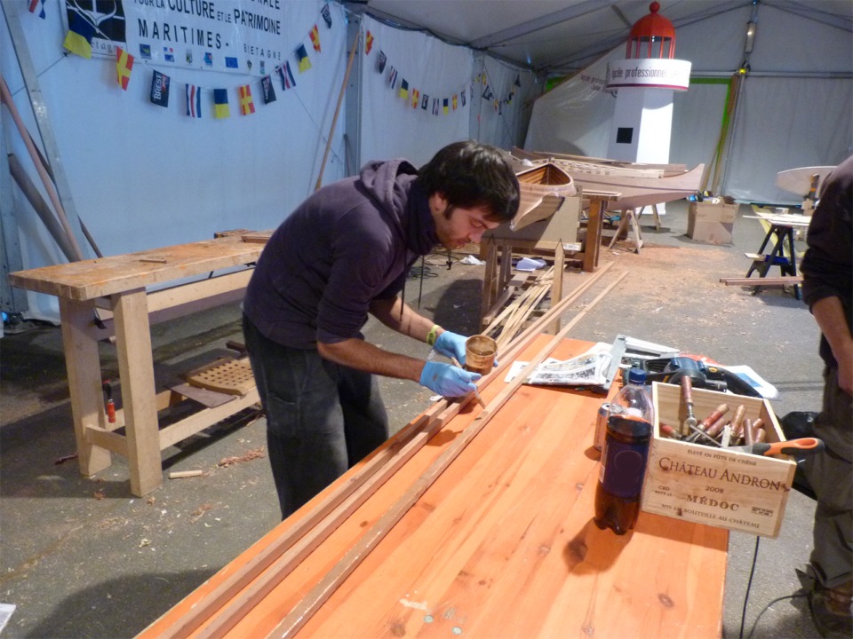 Nous terminons cette troisième journée en collant le premier pli des listons. En effet, ceux-ci sont constitués chacun de deux lattes afin de faciliter leur cintrage. Ici, Yann est en train d'encoller l'une des lattes. 